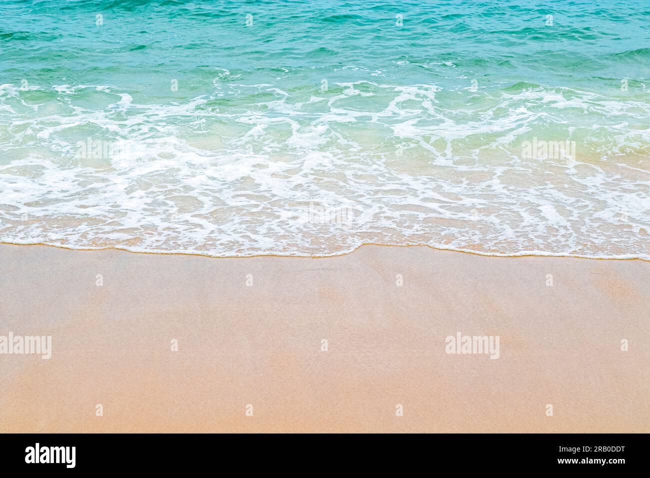Soft blue ocean wave on clean sandy beach. Copy space. Stock Photo