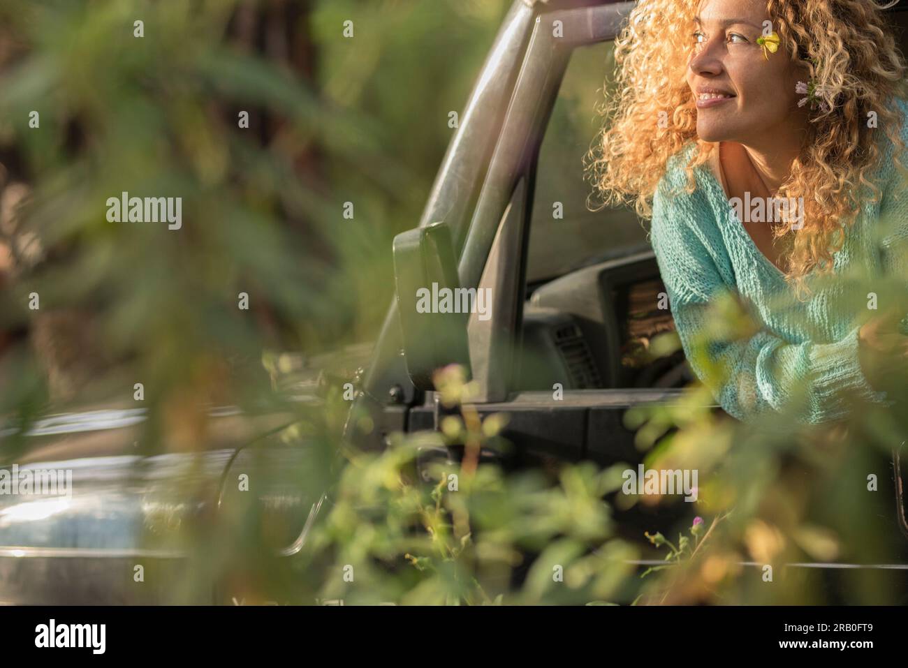 Car travel adventure and love for nature concept lifestyle. One happy woman outside the vehicle window admiring nature around in the bush. Concept of transport and vacation in wild outdoors road trip Stock Photo