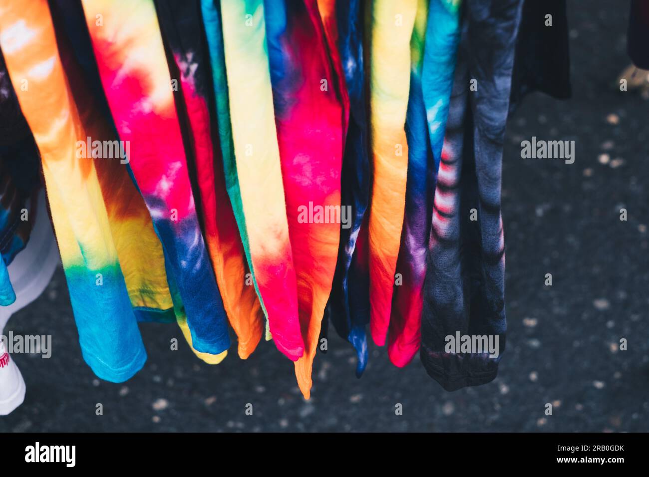 Array of colorful unisex tie-dye shirts. Selective focus. Closeup. Stock Photo