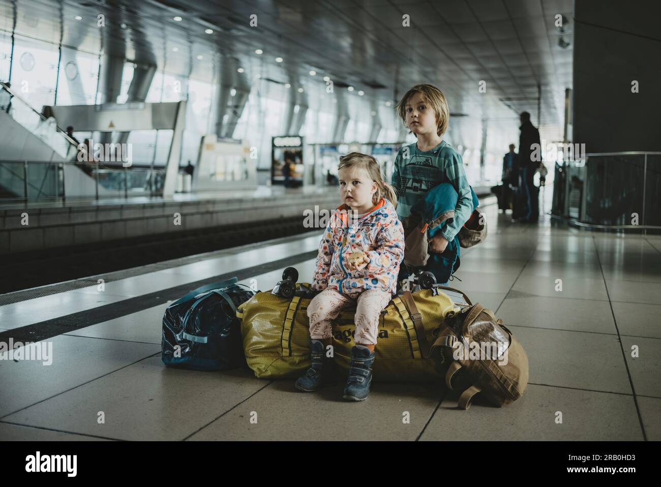 Children sitting on luggage at train station Stock Photo Alamy