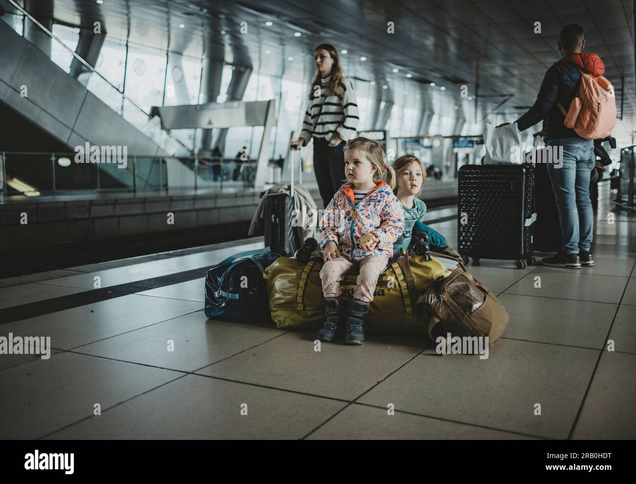 Children sitting on luggage at train station Stock Photo Alamy