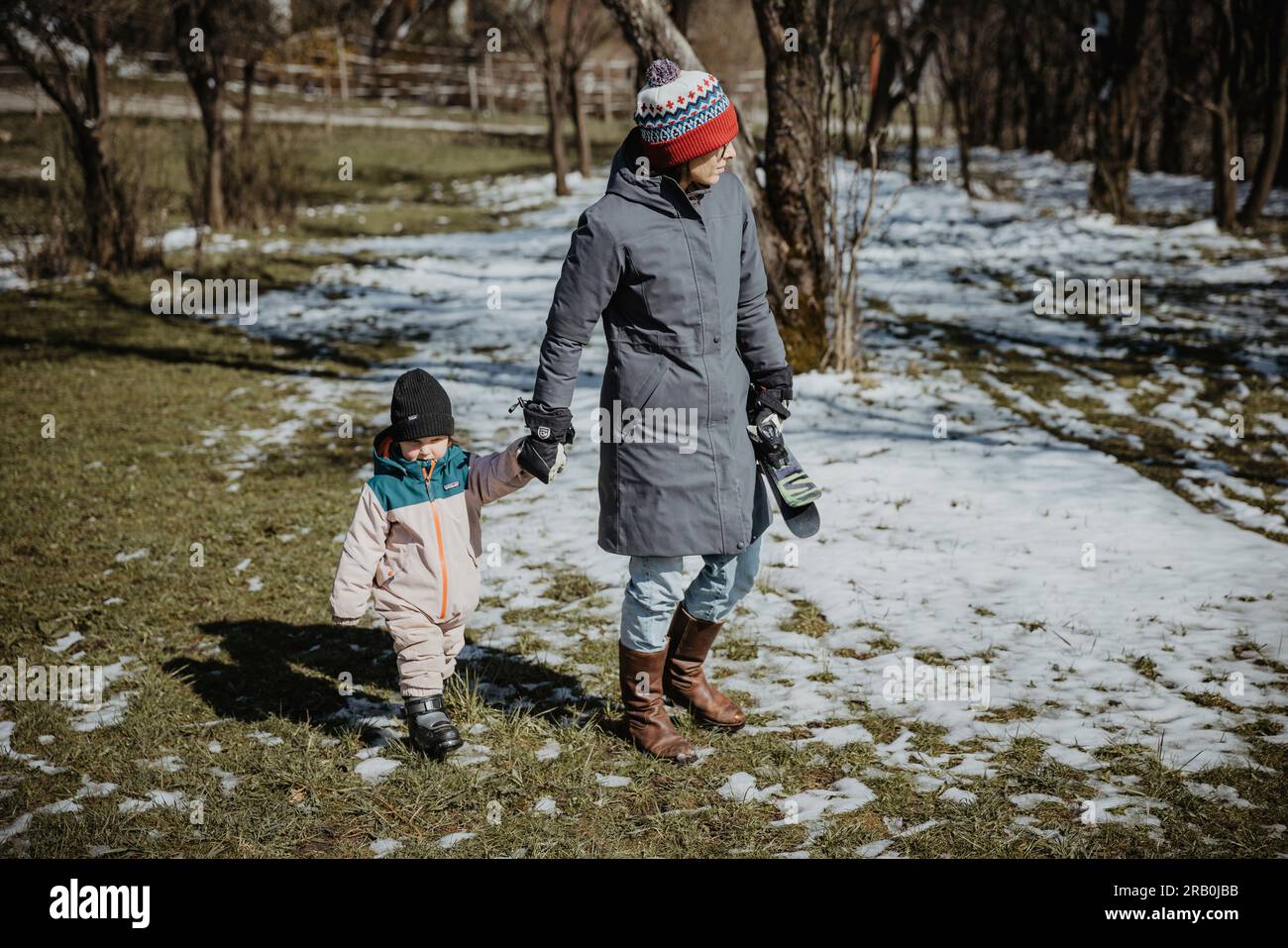 Mother and daughter walking hand in hand across snowy meadow Stock Photo