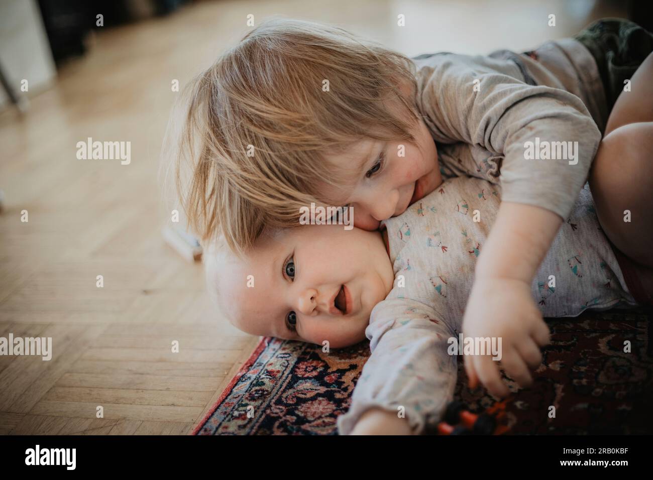 Siblings cuddle on the floor Stock Photo