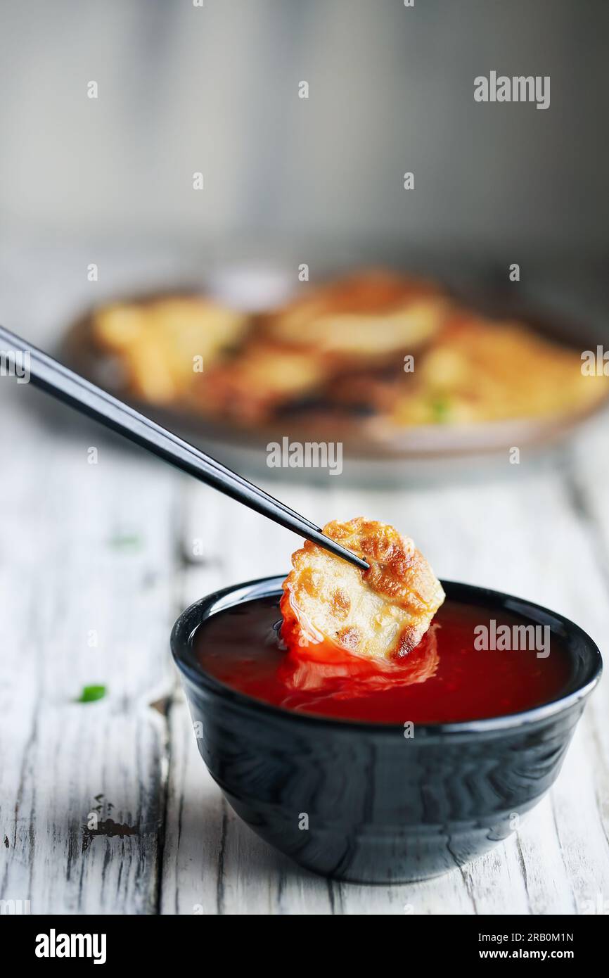 Chopsticks dipping a golden fried Chinese dumpling, also known as Pot
