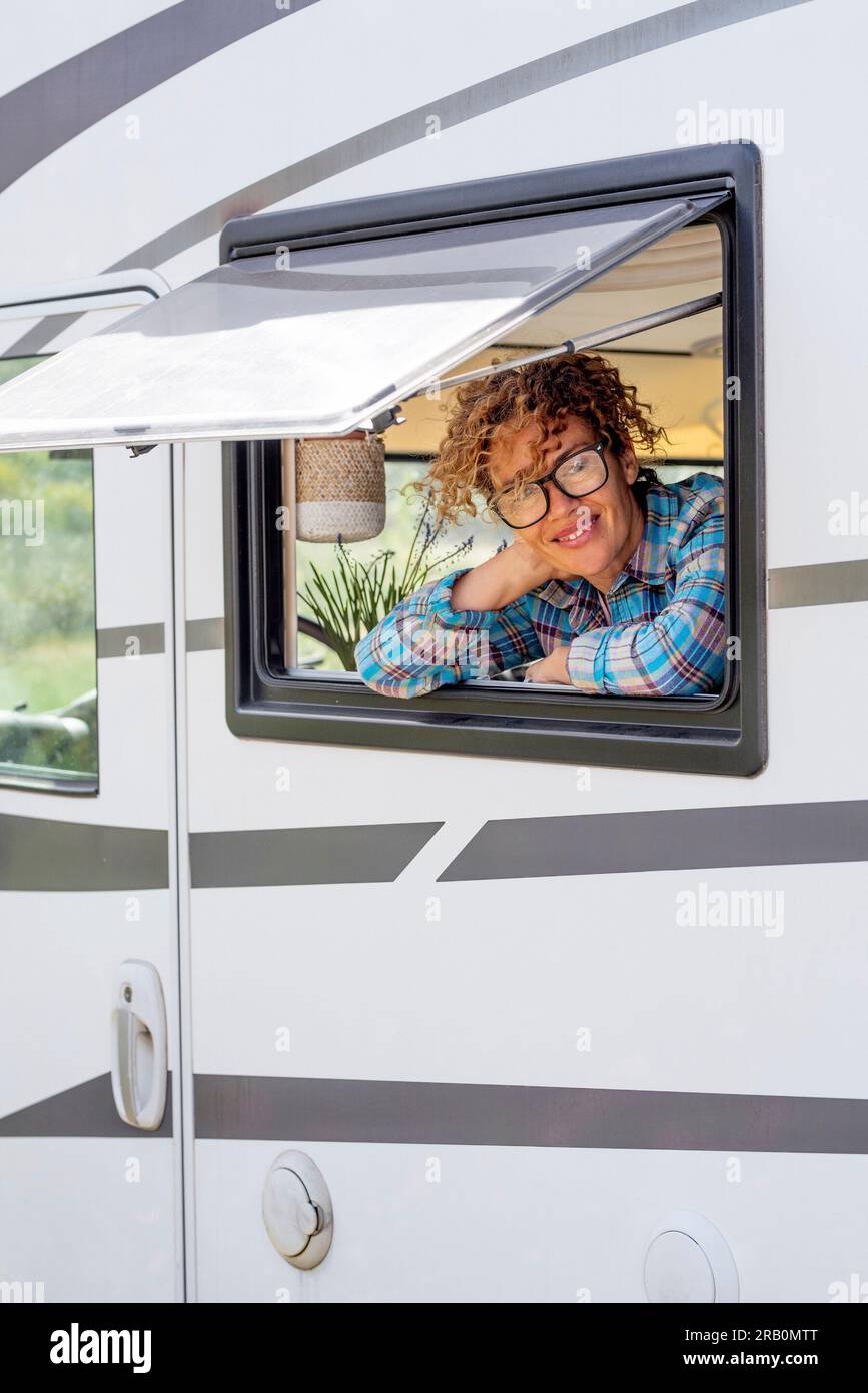 Happy tourist enjoy travel vacation destination inside a modern camper van looking on camera outside the window. Alternative free nomadic people lifestyle in camper van. Adventure holiday vanlife Stock Photo