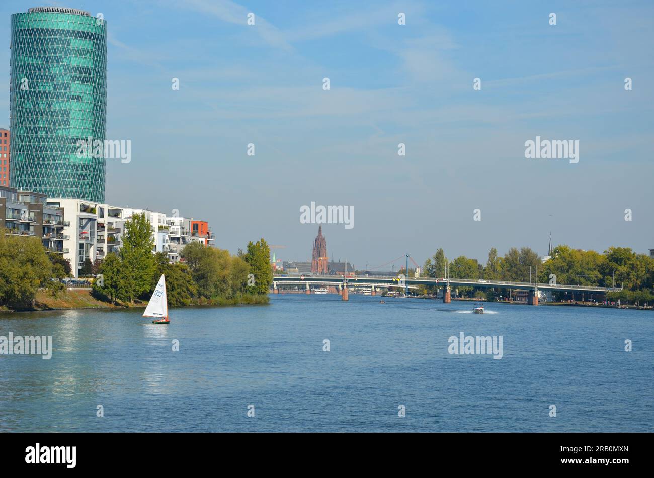 View over the Main river in Frankfurt with a sailboat and some bridges. In the background the tower of the Kaiserdom St. Bartholomäus Stock Photo