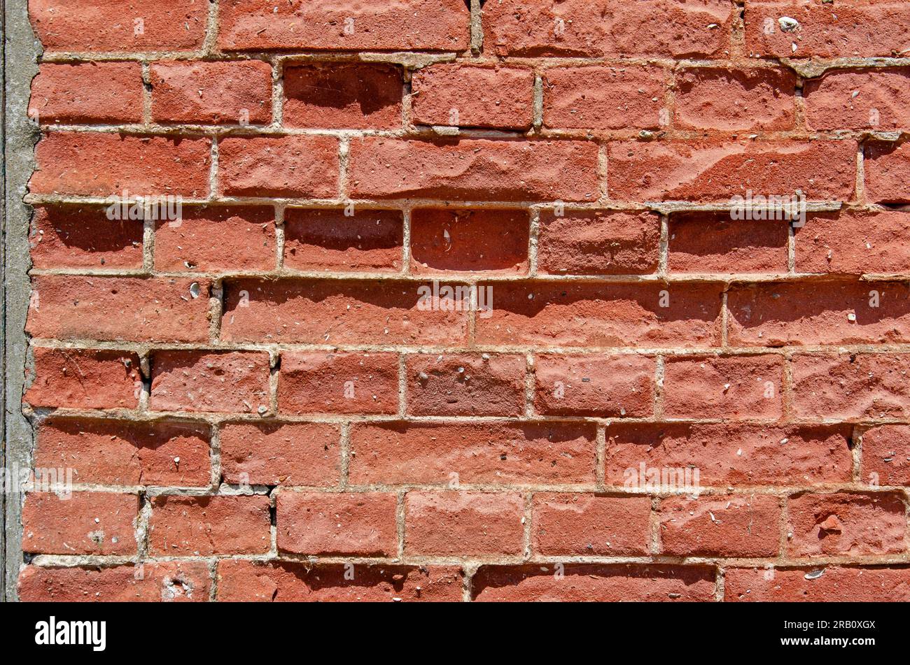 Old and damaged wall with red bricks and light grey mortar Stock Photo
