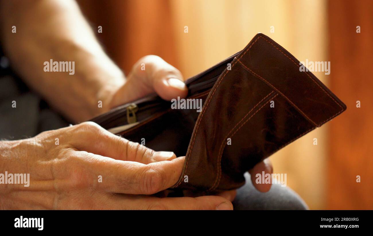 An elderly man's hands, covered with knotted veins, search for coins in his wallet Stock Photo