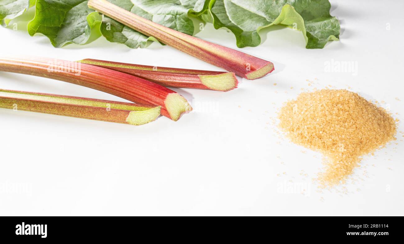Healthy food. Rhubarb stalks and a bunch of brown sugar on a white background. Stock Photo
