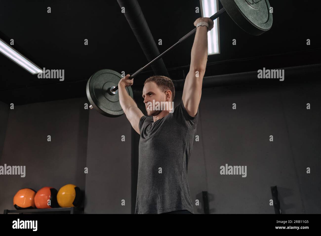 Portrait of muscular weightlifter doing an exercise with a barbell