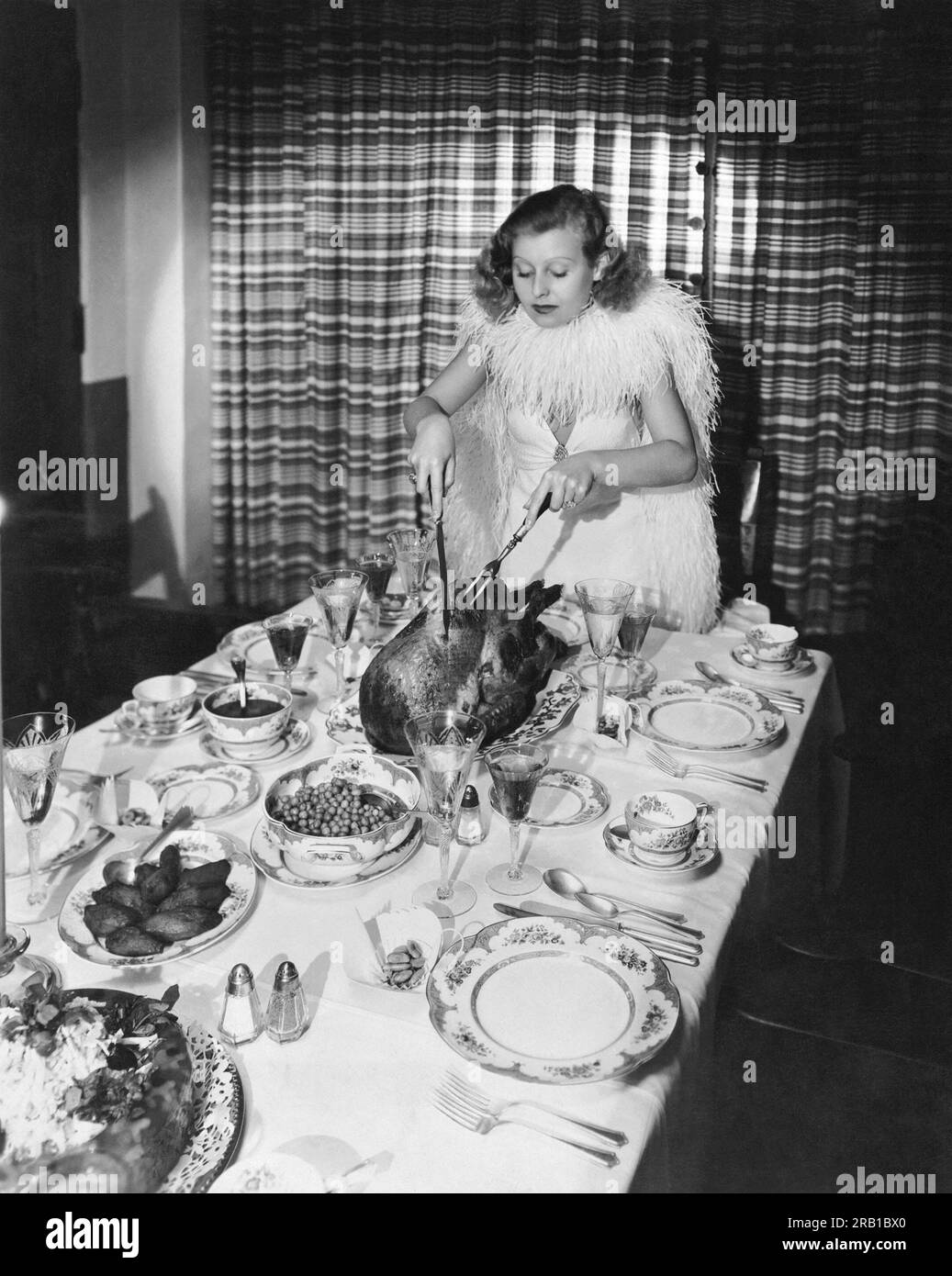 Hollywood, California: c 1932 Fox actress Lilian Harvey carves the