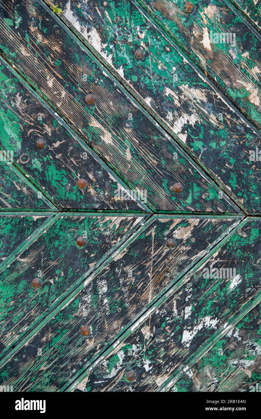 fading green paint on an old wooden door, herringbone pattern, peeling paint, weathered wooden