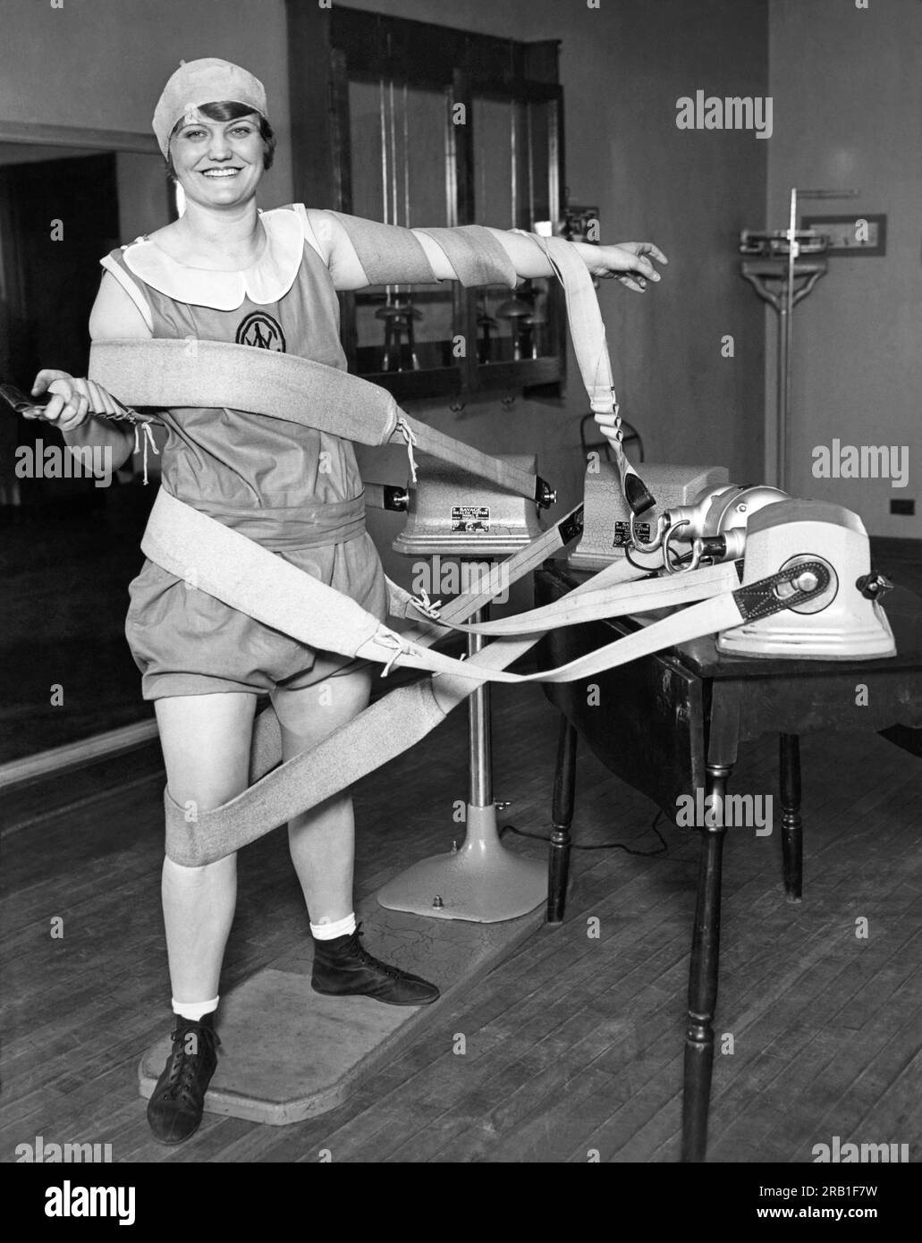 Chicago, Illinois:  May 9, 1929. A woman is tangled up in the straps from the tummy shimmy machines at her athletic club. Stock Photo