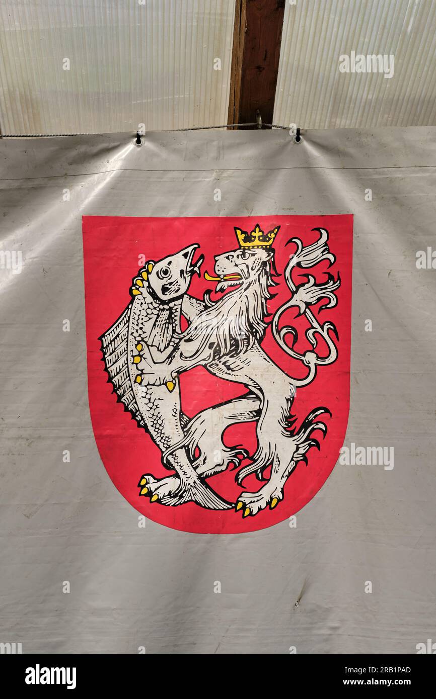 Decin, Czech Republic: The coat of arms of the city of Decin (Tetschen). Upright crowned two-tailed white lion licking a fish on a red background. Stock Photo