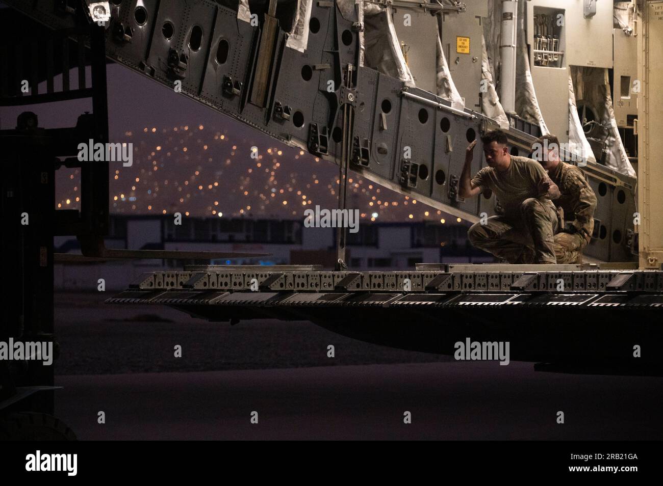 Two Air Foirce loadmasters direct a forklift to the ramp of a C-17 ...