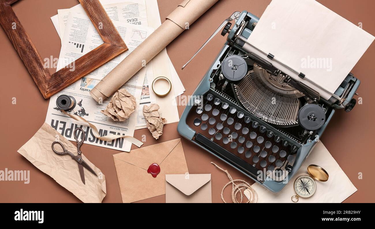 Vintage typewriter, envelopes, paper, newspaper and scissors on brown background Stock Photo