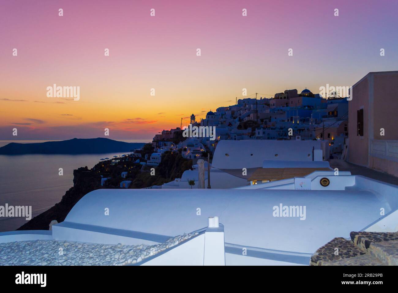 Colorful sunset skies over Mediterranean Sea and Imerovigli luxury resort village on the cliff top overlooking the Caldera,Santorini,Greece Stock Photo