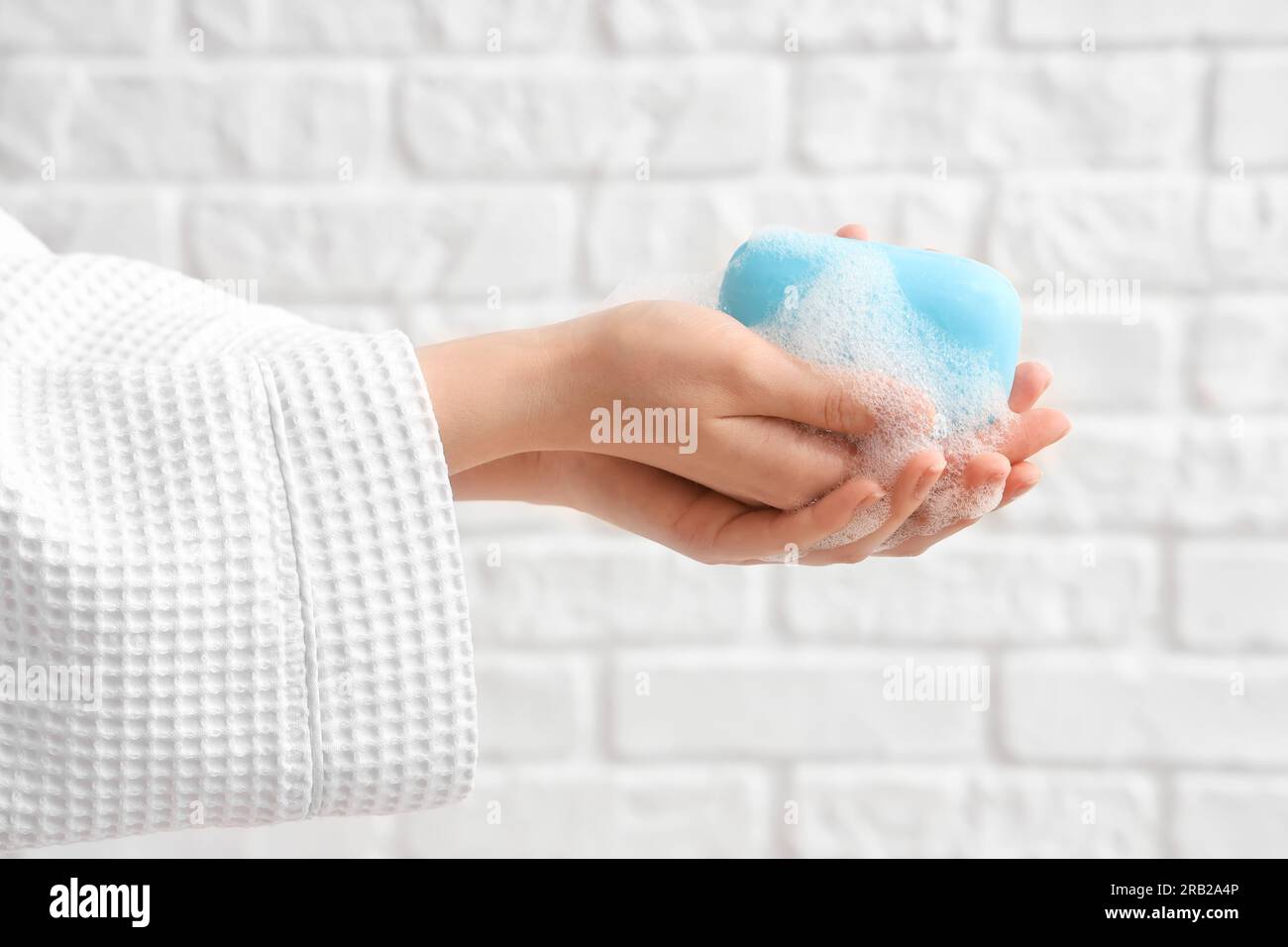 Hands with soap on white brick background Stock Photo