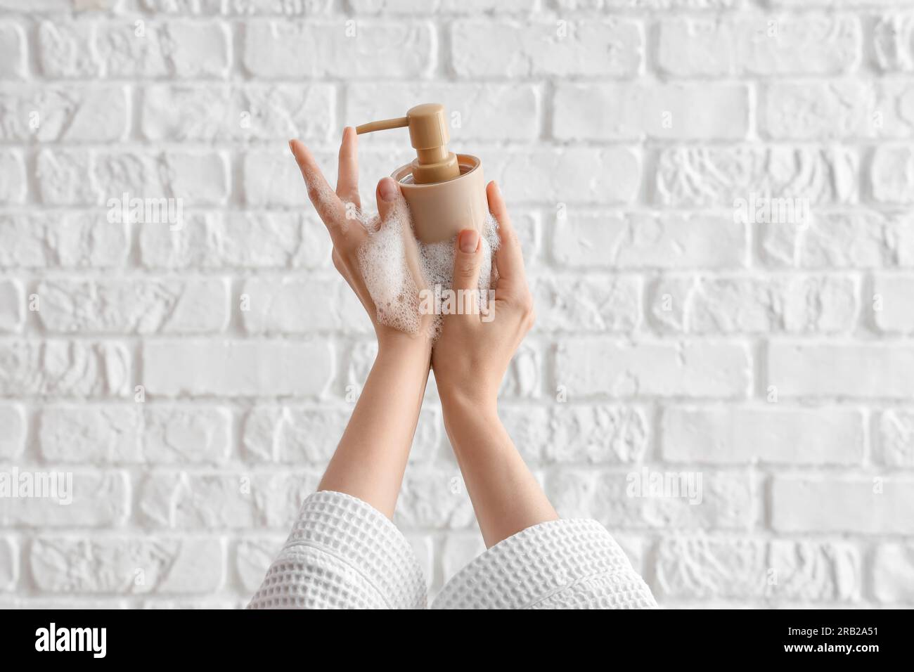 Hands with liquid soap on white brick background Stock Photo