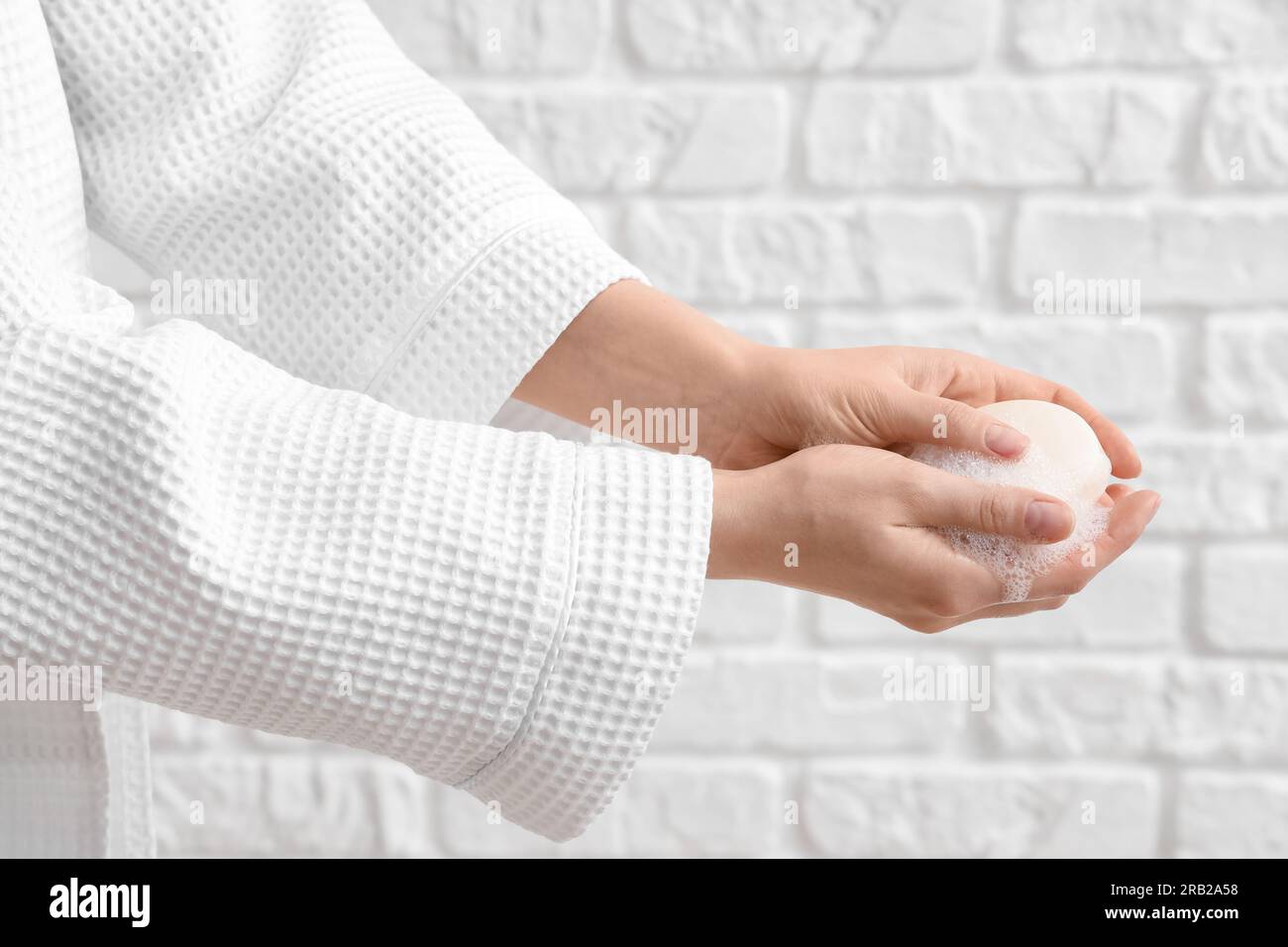 Hands with soap on white brick background Stock Photo