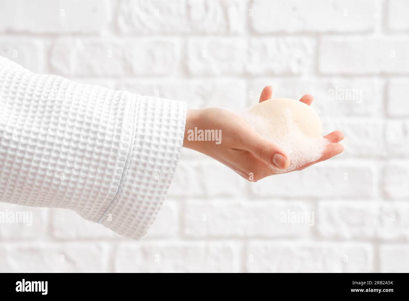 Hand with soap on white brick background Stock Photo