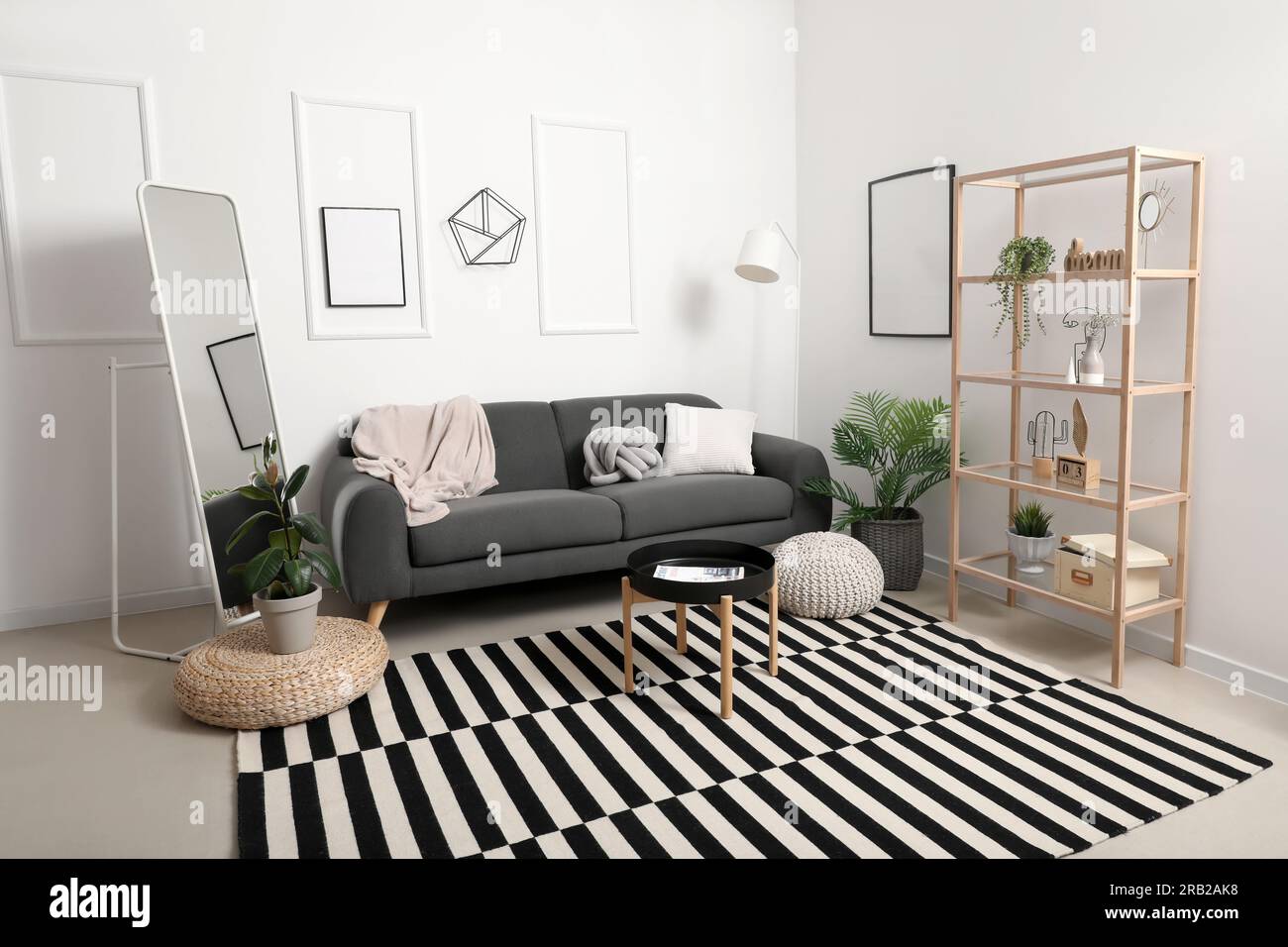 Interior of light living room with grey sofa, mirror and coffee table ...