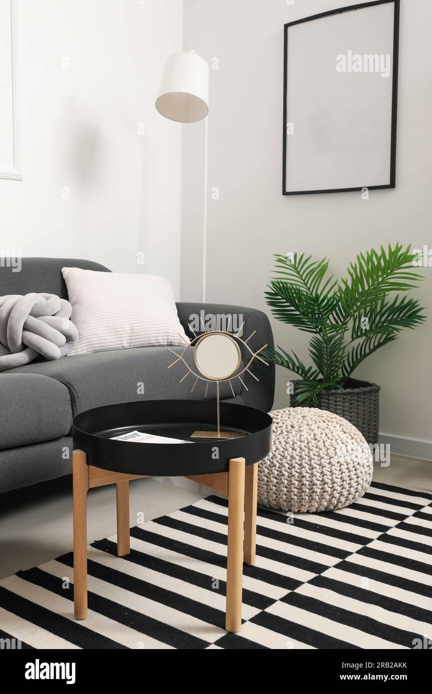 Interior of light living room with grey sofa and mirror on coffee table ...