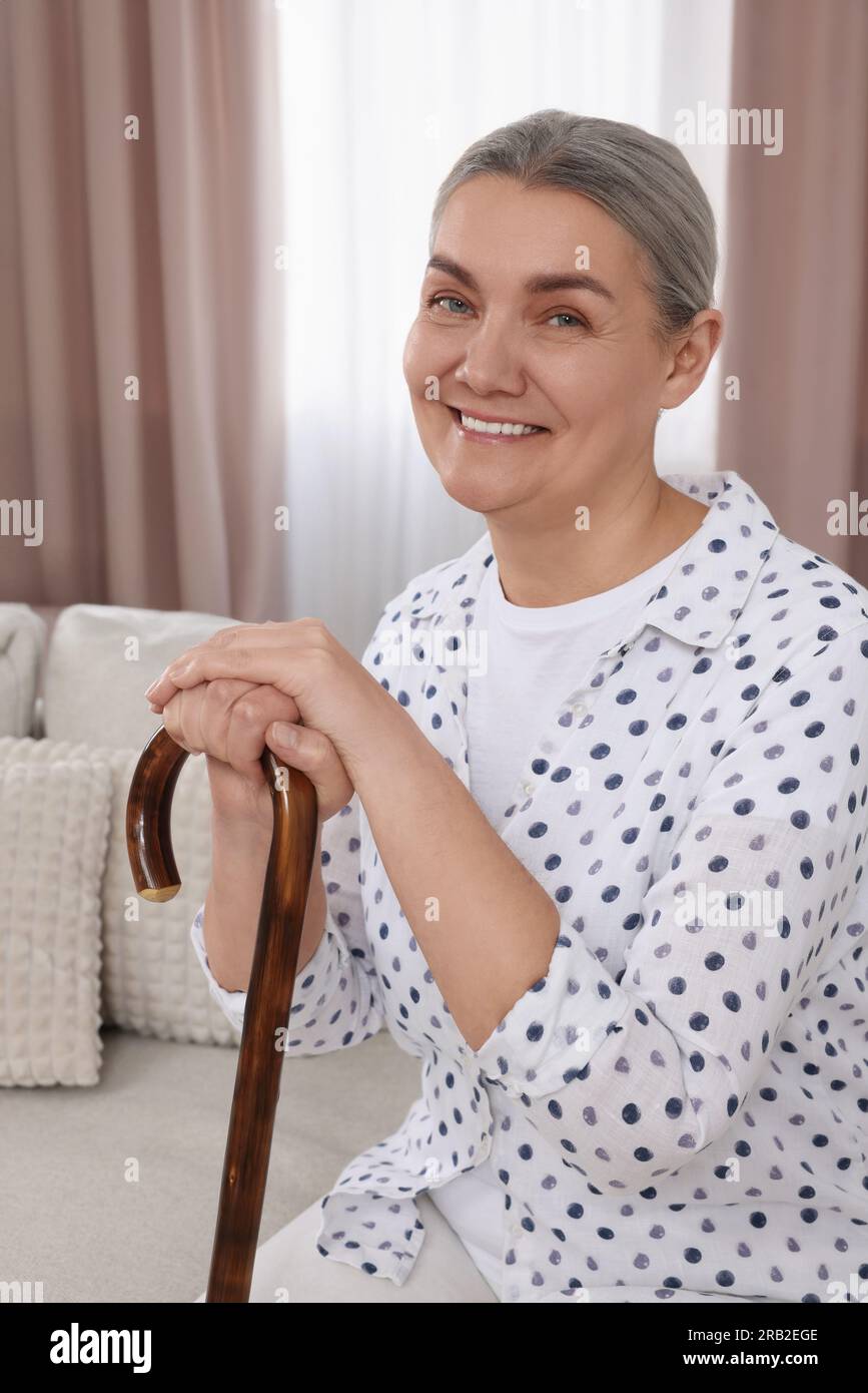 Senior woman with walking cane sitting on sofa at home Stock Photo - Alamy