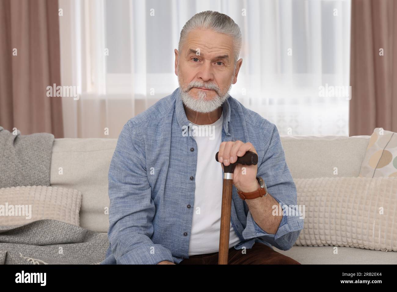 Senior man with walking cane sitting on sofa at home Stock Photo - Alamy