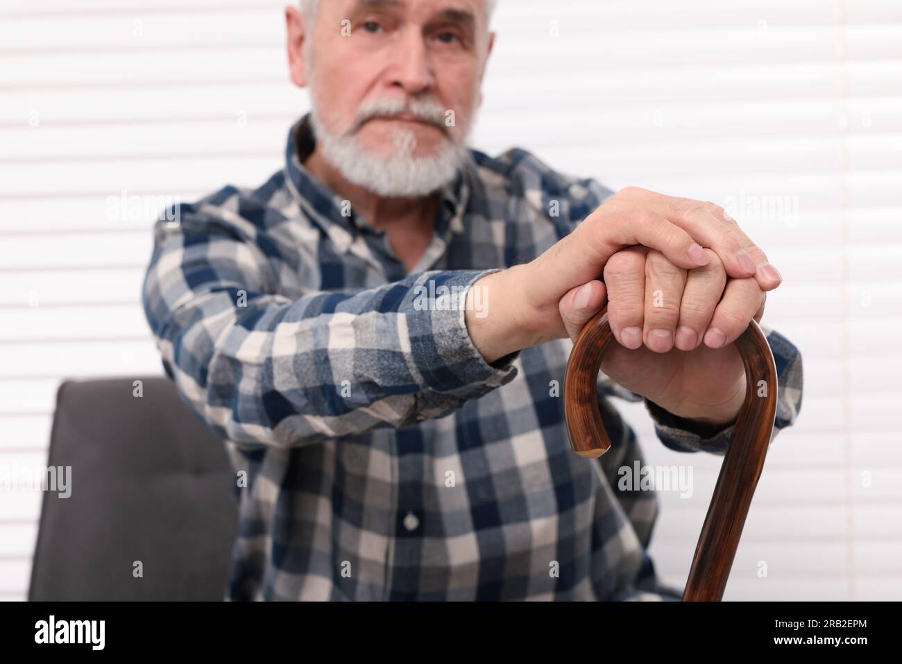 Senior man with walking cane sitting on armchair at home Stock Photo ...