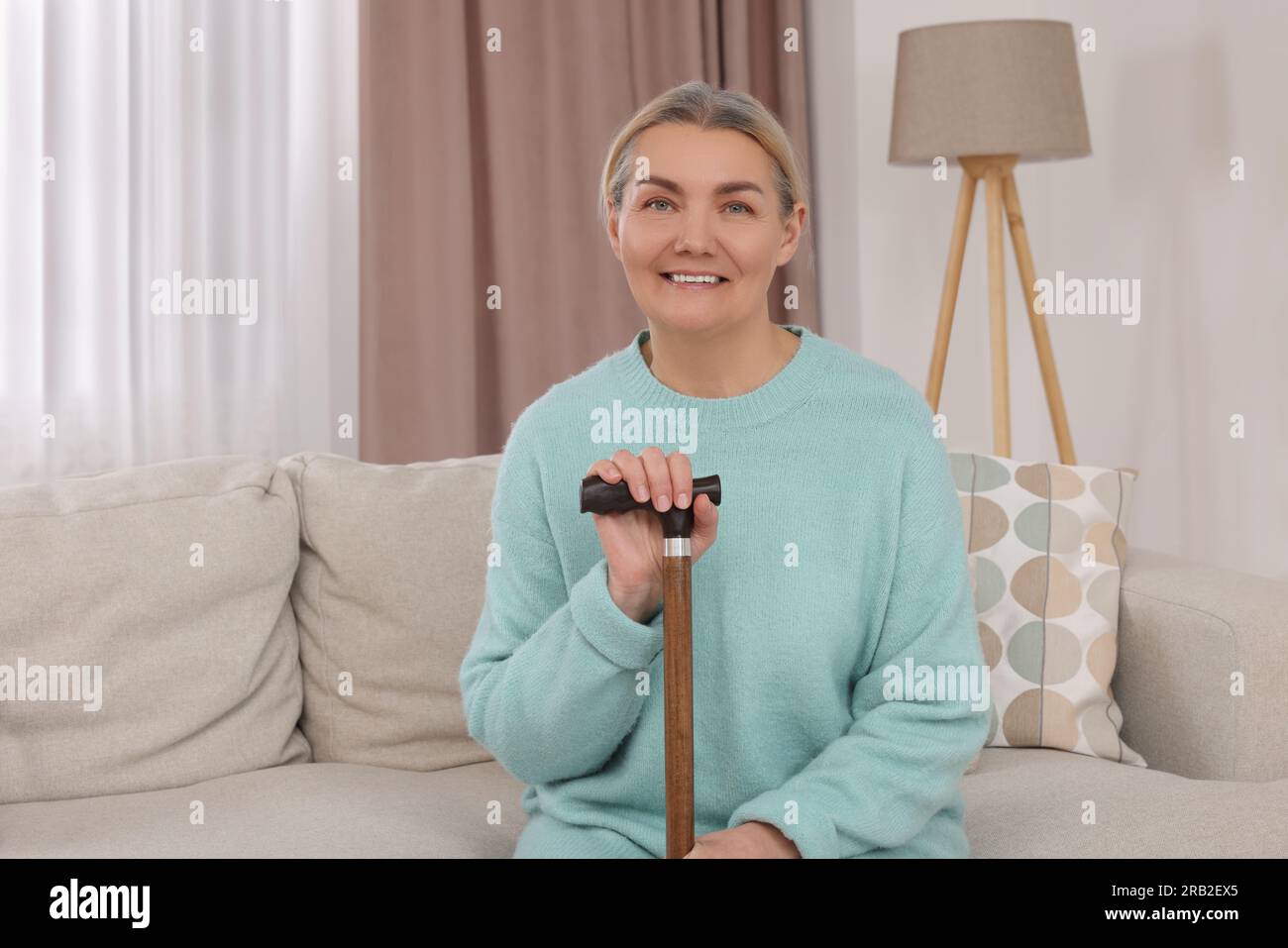 Senior woman with walking cane sitting on sofa at home Stock Photo - Alamy