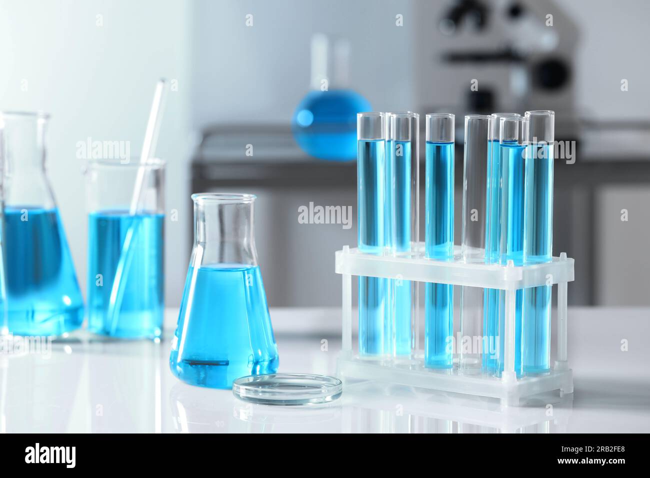 Test tubes with light blue liquid and different laboratory glassware on ...