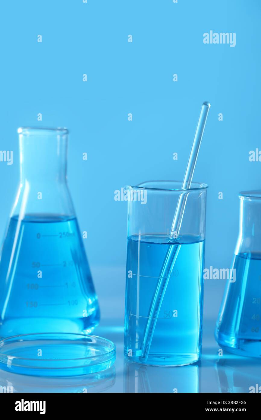 Different laboratory glassware with light blue liquid on table Stock ...