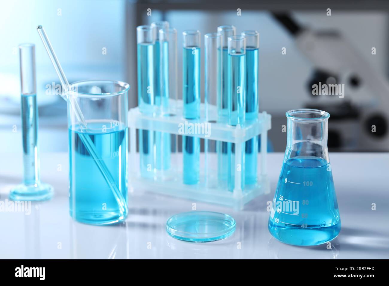 Different glassware and test tubes with light blue liquid on table in ...