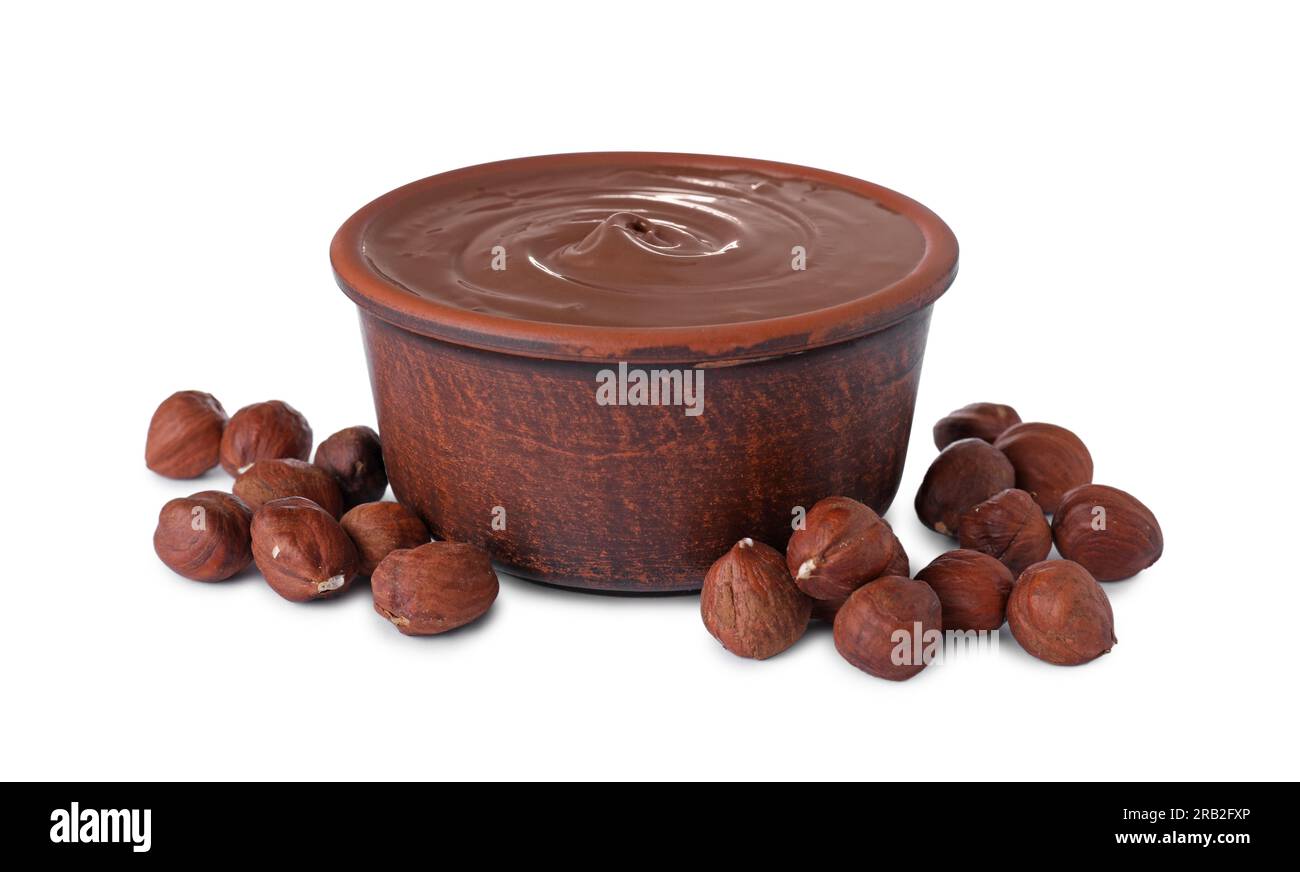 Bowl with delicious chocolate paste and hazelnuts on white background Stock Photo
