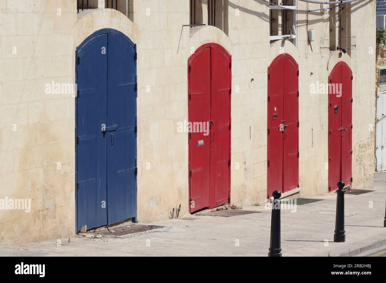 A row of four doors painted in primary colours on a block of lock up