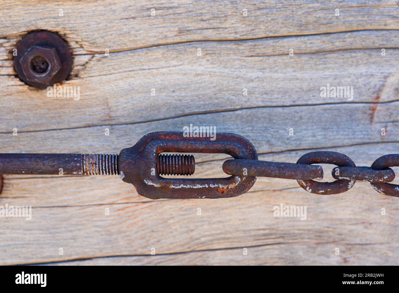Chain links are locked together with a large rusty bolt making a tight