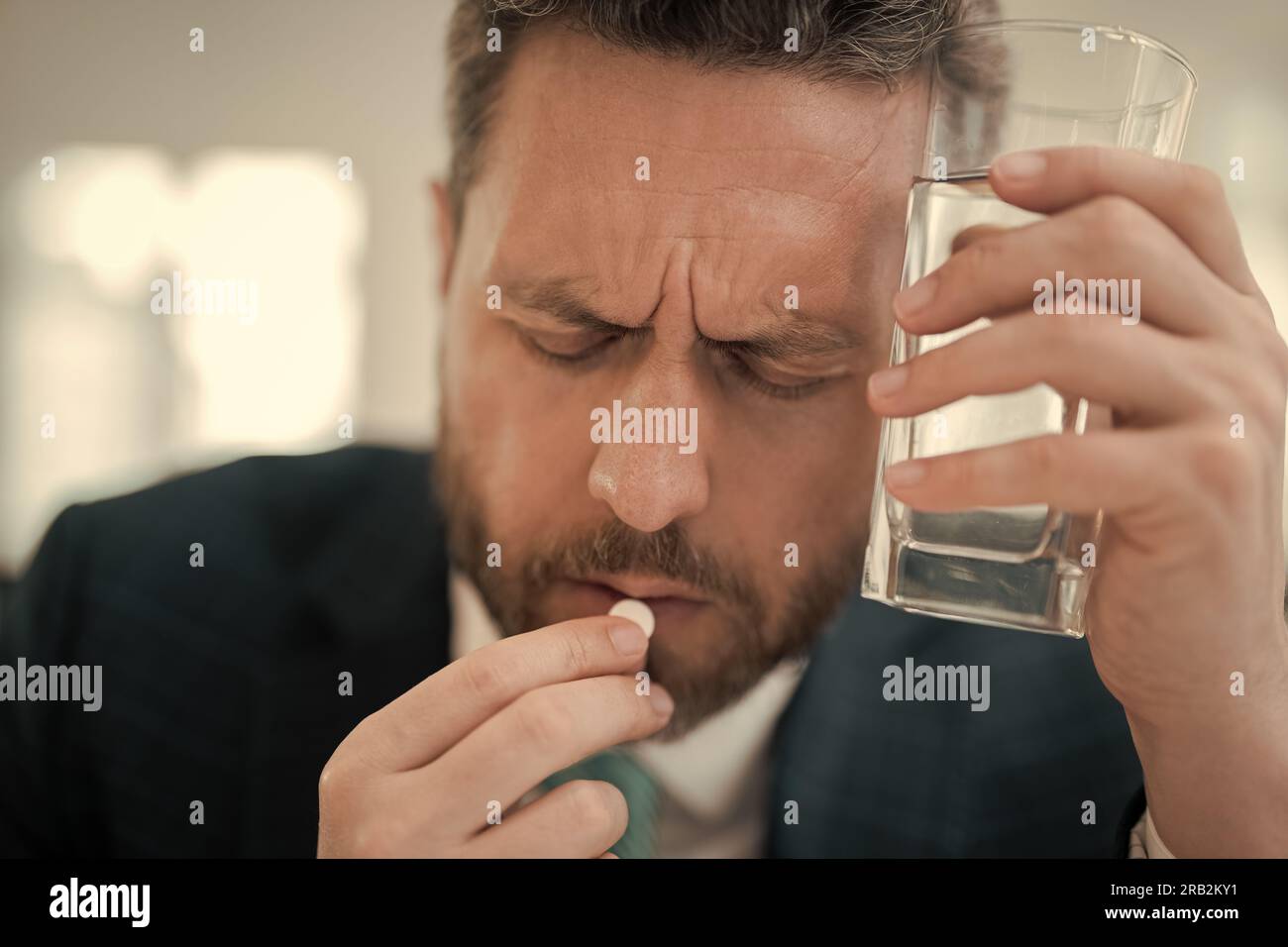 Tired man feel pain holding glasses rubbing dry irritated eyes fatigued from computer work, stressed man suffer from headache. Man taking a Medicine p Stock Photo