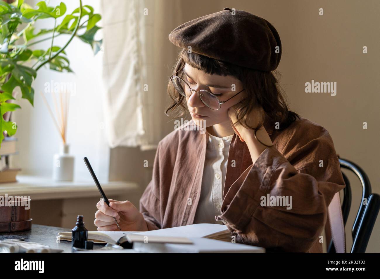 Concentrated artist young woman drawing in notebook with black ink. Art