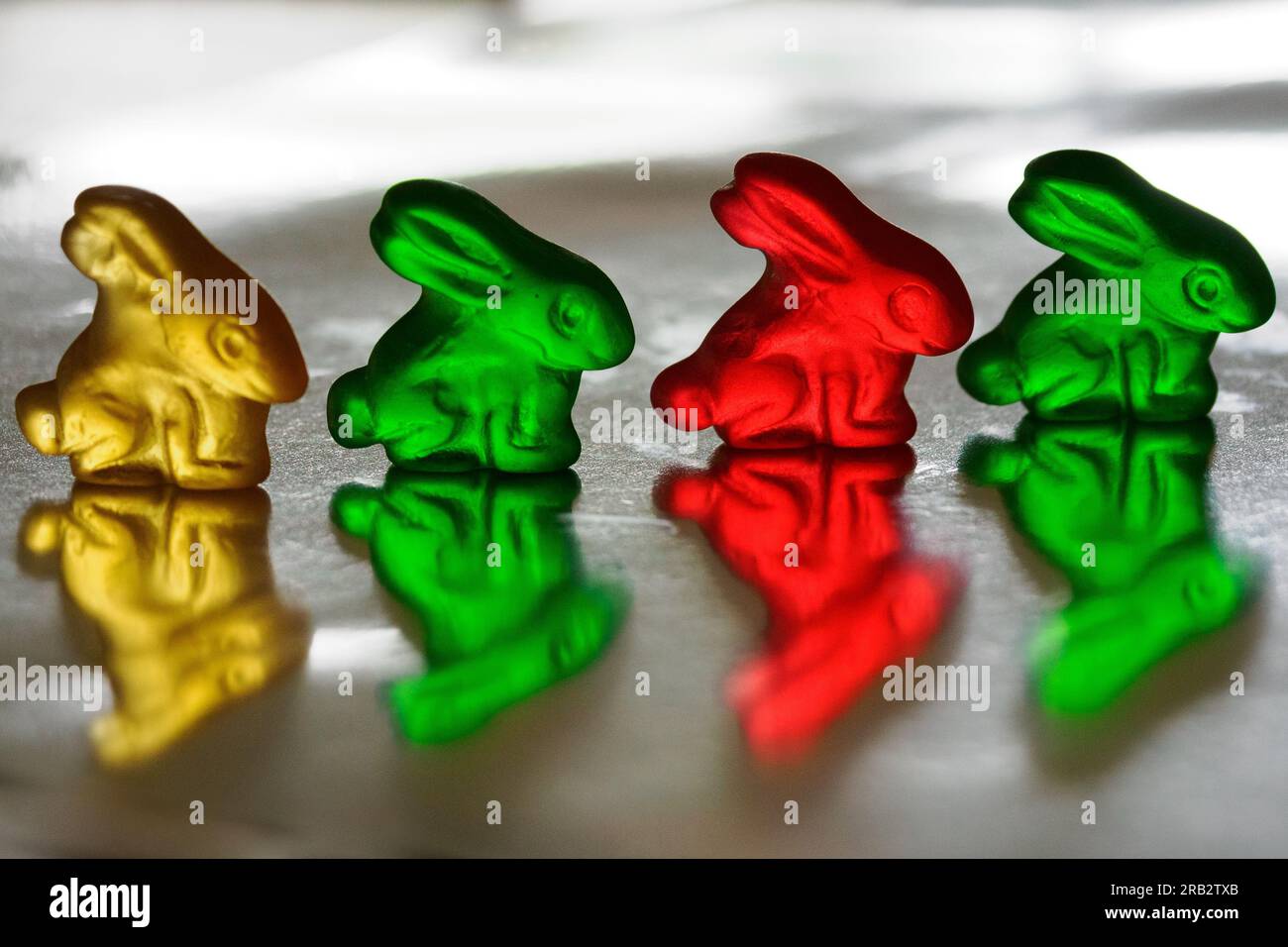 Red, green & yellow gummy bunny candy lined up and reflected in shiny ...