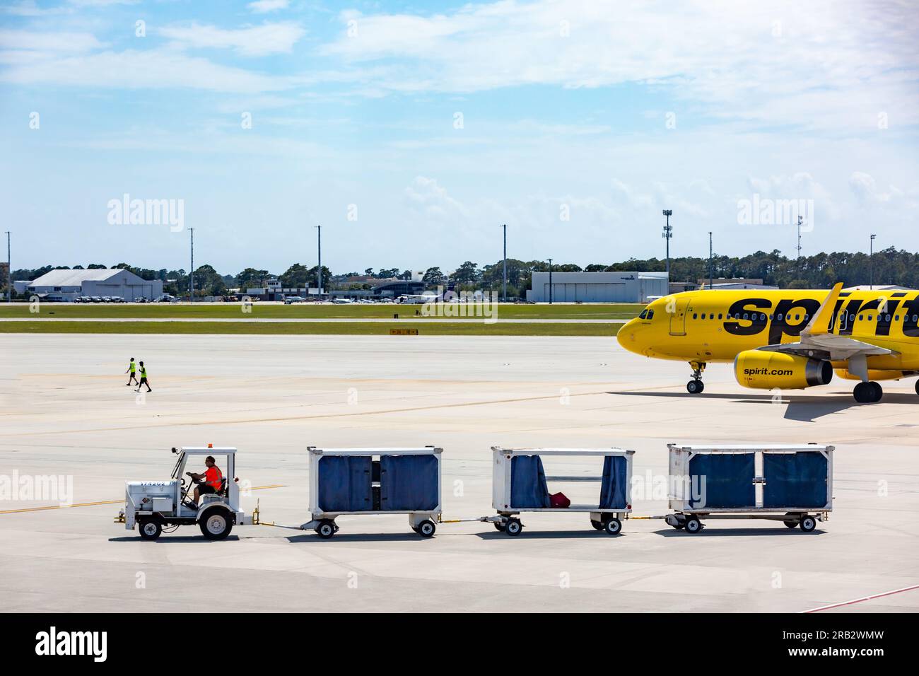 A Unifi Aviation Services tug & baggage cart pass a Spirit Airlines Airbus A320 passenger jet airliner at Myrtle Beach International Airport, SC, USA. Stock Photo
