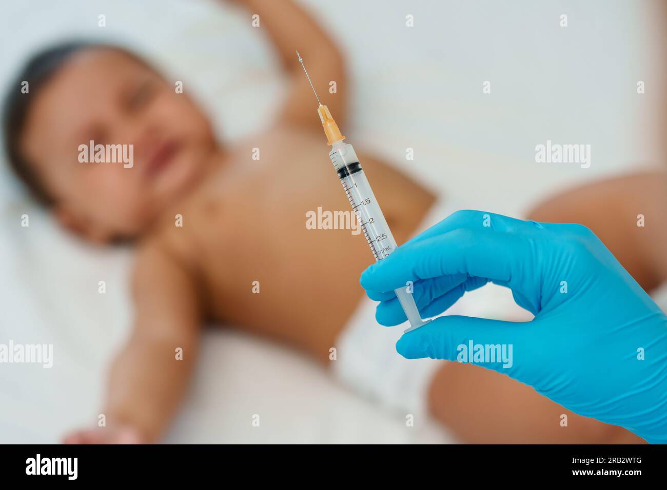 doctor holding syringe and preparing vaccine giving injection to crying infant baby Stock Photo