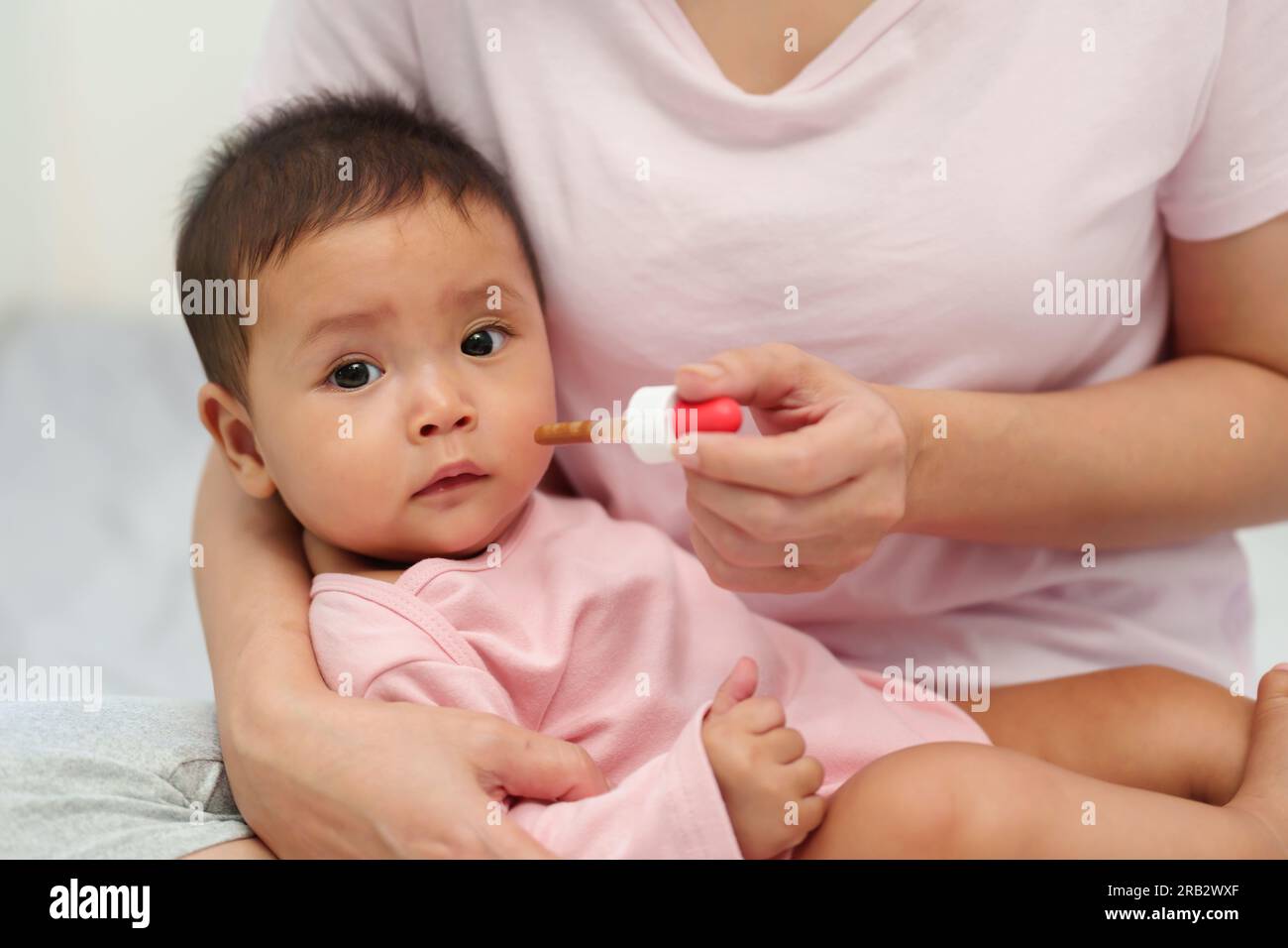 mother feeding a liquid medicine to sick infant baby with a dropper