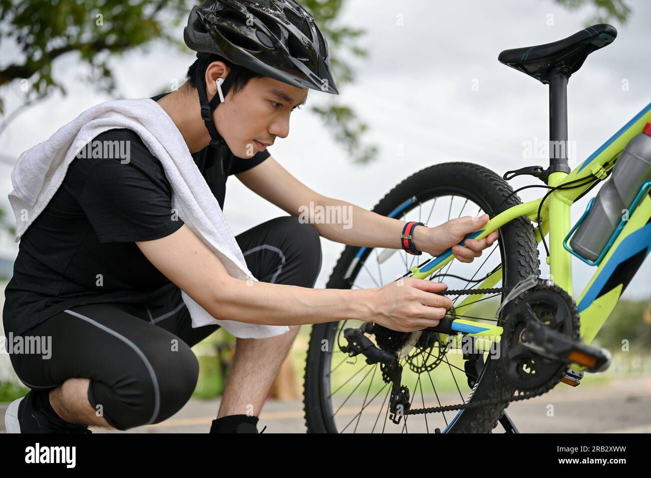 A professional young Asian male cyclist fixes his bike chain on the ...
