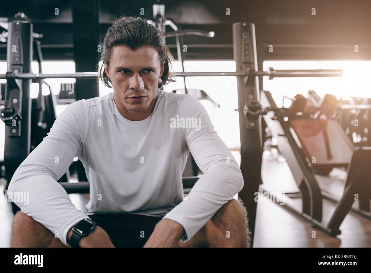 serious sport athlete man fitness trainer sitting in sport club gym body muscle training people Stock Photo