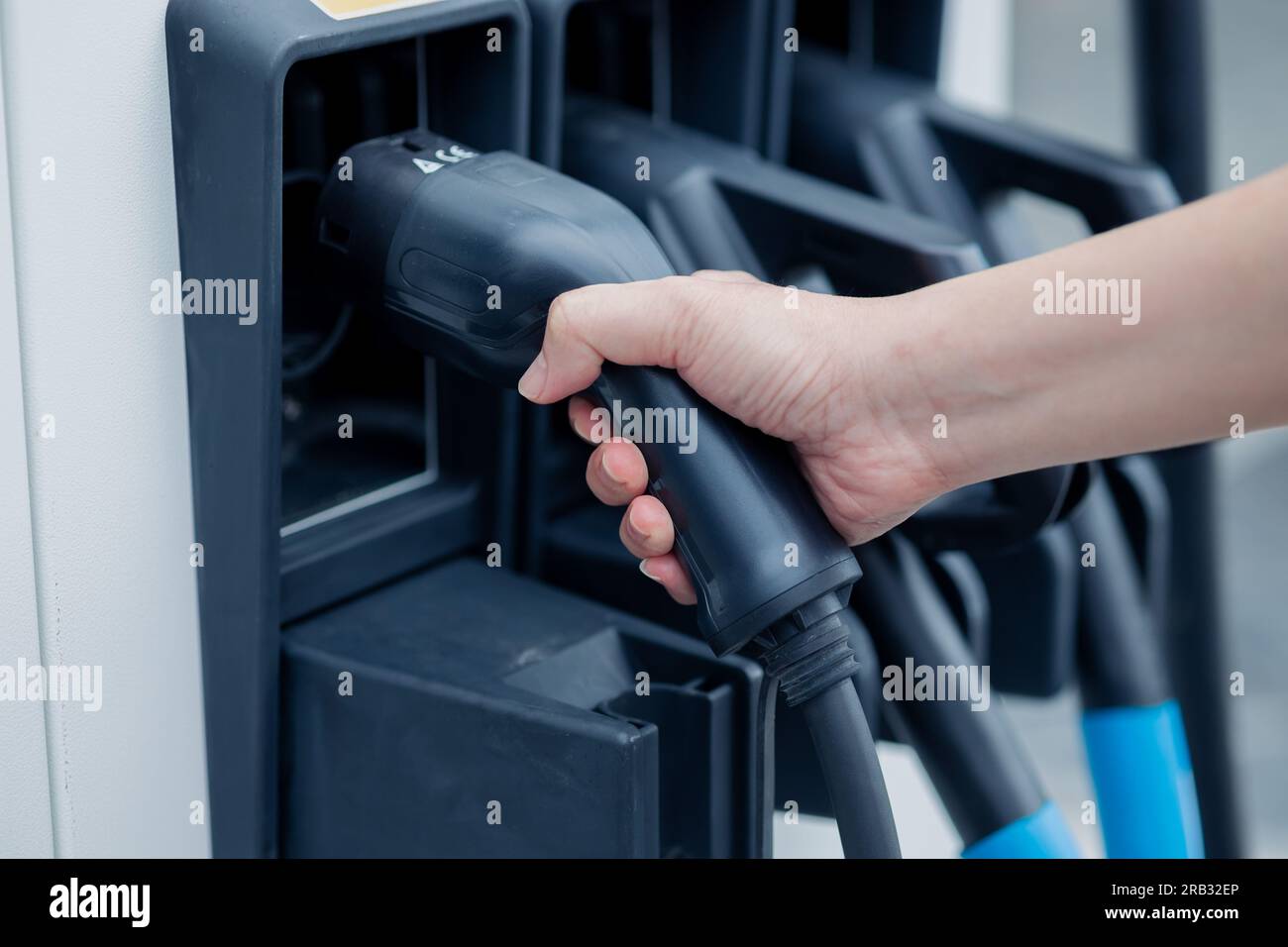 charging EV car electric vehicle clean energy for driving future. hand holding charger head station. Stock Photo