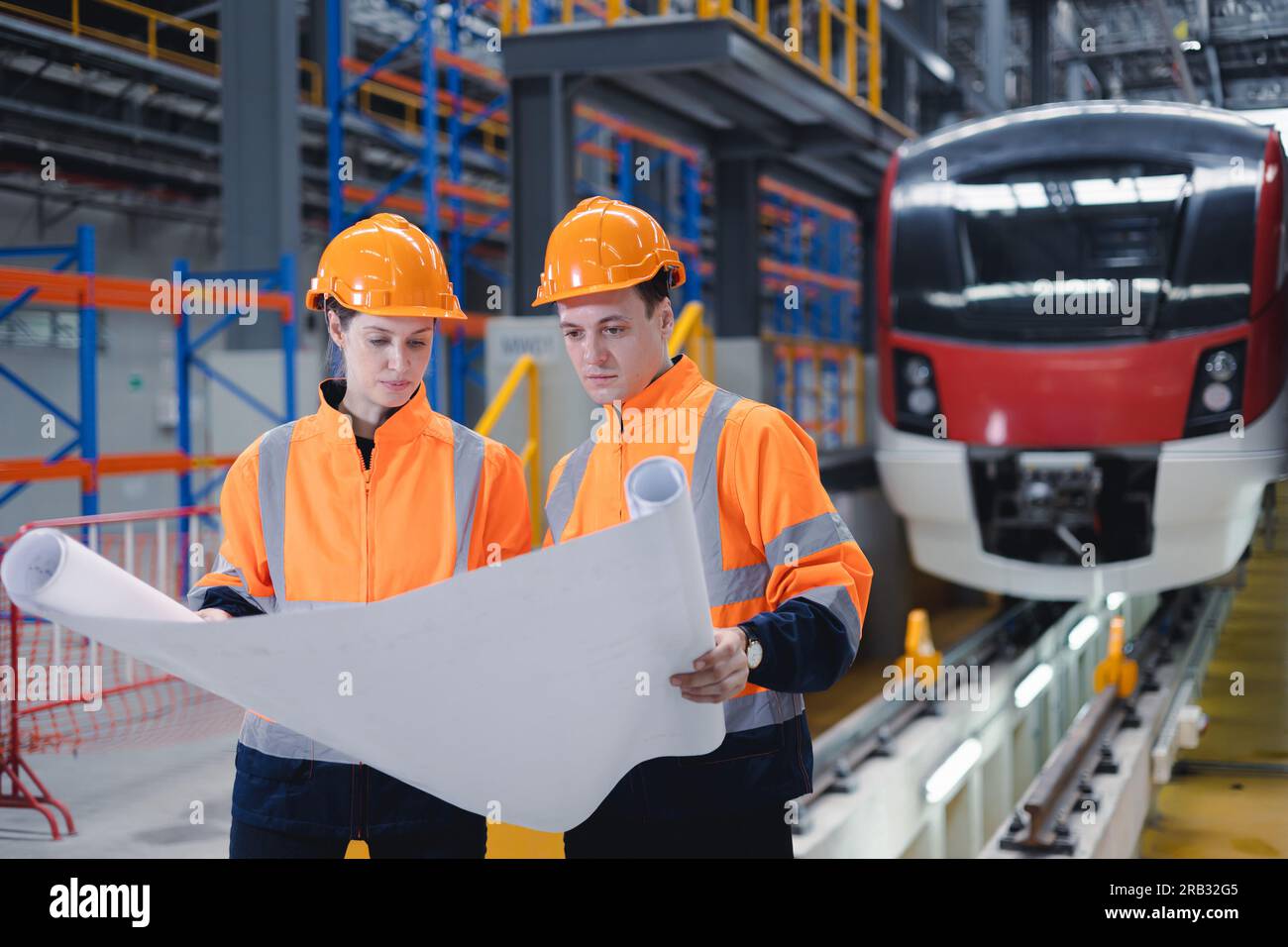 Electric train engineer mechanic staff team worker looking system plan for maintenance schedule check train running service in train factory workshop. Stock Photo
