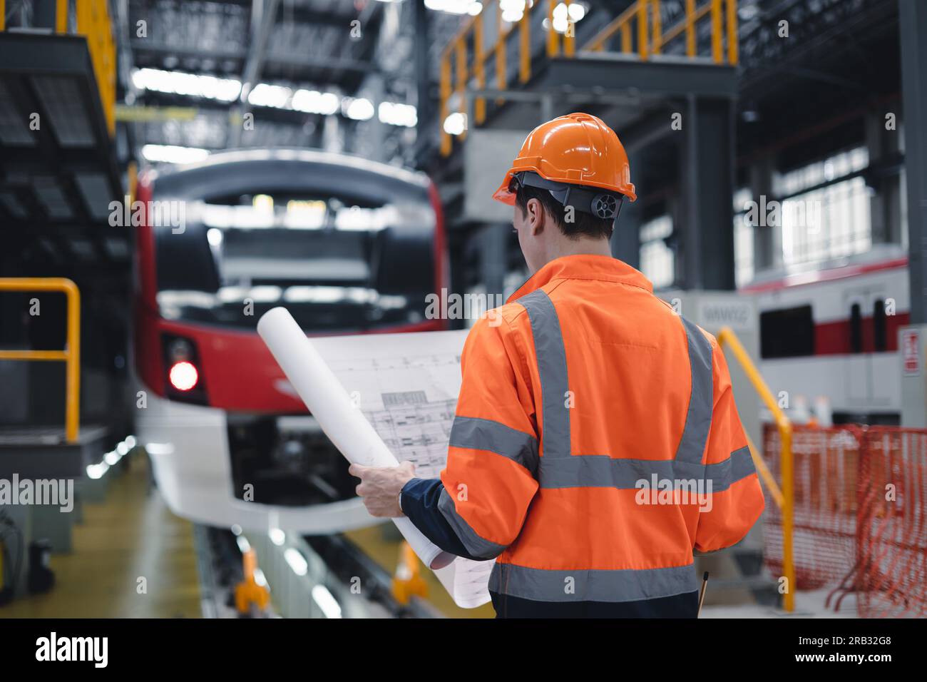 Electric train engineer mechanic staff worker with design plan for maintenance schedule check train running service in train factory workshop. Stock Photo
