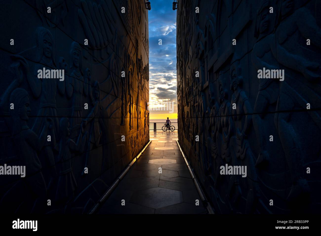 Silhouette of a man with a bicycle at the end of the tunnel of Nghinh Phong tower in Phu Yen province, Vietnam, overlooking the sea at dawn Stock Photo