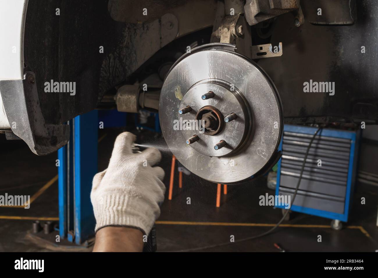 An auto mechanic uses an aerosol can to remove grease from a newly